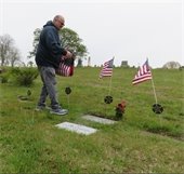 Man placing flags at veterans' graves